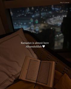 an open book sitting on top of a bed in front of a window with the words raman is almost here