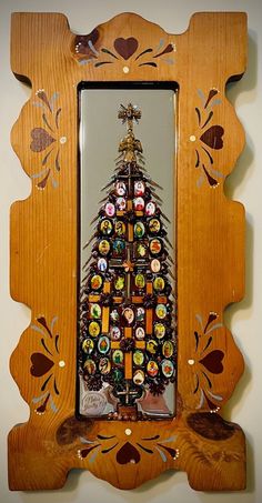 a wooden frame with a christmas tree made out of bottle caps in the shape of a mirror