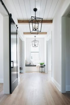 an empty room with white walls and wood floors, light fixture hanging from the ceiling