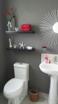 a white toilet sitting next to a bathroom sink under a sunburst shaped mirror