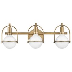 three light bathroom fixture in an antique brass finish with white glass balls on the sides