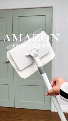 a person holding an amazon cleaning mop with the handle extended to it's side