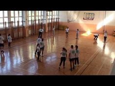 a group of people standing on top of a gym floor with basketballs in the air