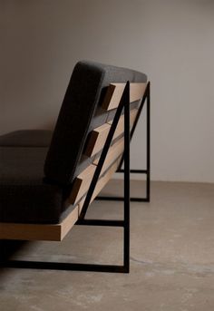 a black bench sitting on top of a floor next to a white wall in a room