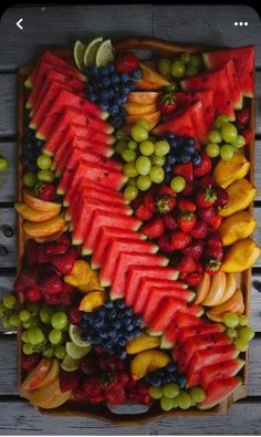 a wooden tray filled with lots of different types of fruit on top of each other