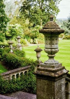 an old stone lamp post sitting in the middle of a lush green park