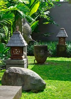 an outdoor garden with rocks and plants in the grass, including two bird houses on top of them