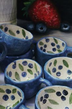 blueberries and strawberries are painted on ceramic bowls