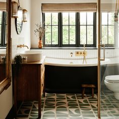 a bath room with a toilet a sink and a bath tub next to a window