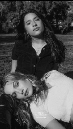 two young women laying on the ground in black and white photo with trees behind them