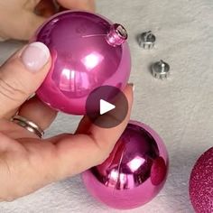 someone is holding two pink ornaments in their hand