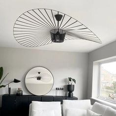 a living room filled with furniture and a round mirror on the wall over a window