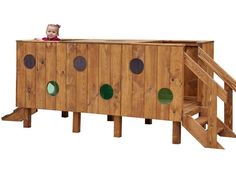 a toddler sitting on top of a wooden play structure with green circles around it