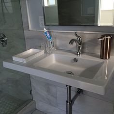 a bathroom sink with soap and toothbrushes on the counter top next to it