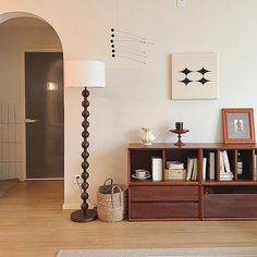 a living room filled with furniture and a lamp on top of a hard wood floor