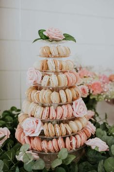 a stack of macaroons with pink roses on top and greenery in the background