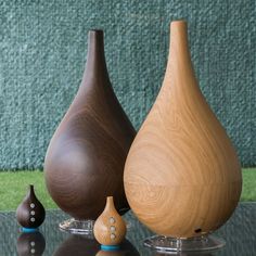 three wooden vases sitting on top of a glass table next to each other,