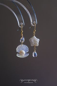 ---- Welcome to CiaoQiao Shop ----- These stunning, sea-inspired dangle earrings crafted with delicate care, each earring features a shimmering pearl nestled in a lustrous shell, complemented by a cascade of blue crystal droplets that reflect the tranquil hues of the sea. The iridescent glow of the shells and pearls brings a natural, serene beauty to any ensemble. Perfect for beach weddings, seaside events, or adding a splash of oceanic charm to your everyday wear. Length including hooks: 1 1/2" | 3.8cm Please note: natural pearls will have flaws and each is unique. Tips for making your Jewelry last longer - Remove your jewelry before you swim in chlorine or salt water. - Remove your jewelry before participating in activities that will cause you to sweat a lot. - Wait to put on your jewelr Luxury Ocean-inspired Earrings For Gift, Ocean-inspired Dangle Single Earring, Ocean-inspired Single Dangle Earring, Ocean-inspired Dangle Pearl Drop Jewelry, Ocean-inspired Pearl Drop Dangle Jewelry, Ocean-inspired Dangle Shell Earrings, Ocean-inspired Shell Dangle Earrings, Shell Dangle Earrings, Shells And Pearls