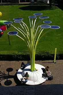 two children are sitting on the ground in front of a tree with solar panels attached to it