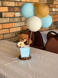 a teddy bear sitting on top of a table with balloons in the shape of flowers