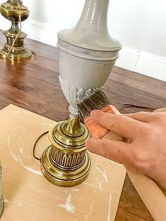 a person painting a lamp on a wooden table