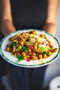 a person holding a plate full of food with sprouts and nuts on it