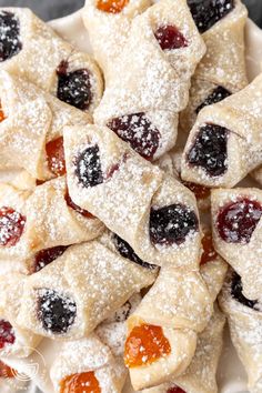 a white plate topped with pastries covered in powdered sugar and jelly toppings