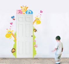 a young boy walking past a door with giraffes and monkeys on it