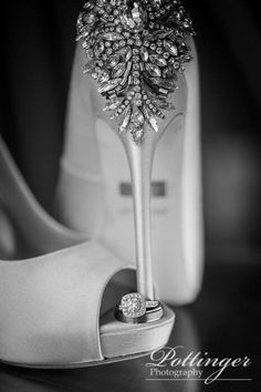 a pair of wedding shoes and ring on top of a shoe with a flower in the middle