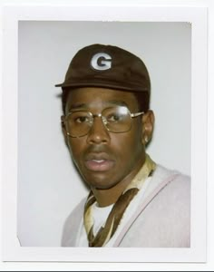 a man wearing glasses and a hat with the letter g on it's cap