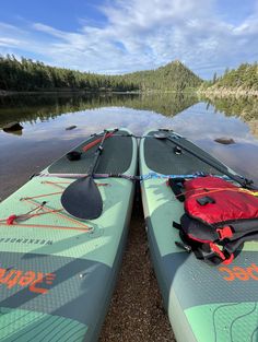 two kayaks sitting on the shore of a lake