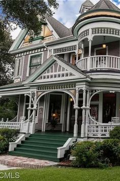 an old victorian style house with green trim and white balconies on the front porch