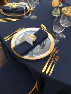 the table is set with gold and black place settings, silverware, and napkins