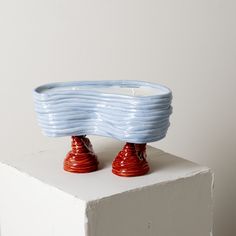 two red and blue vases sitting on top of a white block in front of a white wall