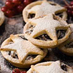 several pastries are arranged on a table with cherries and powdered sugar around them