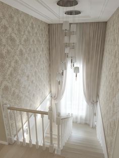 an empty staircase leading up to a window with drapes on the windowsills