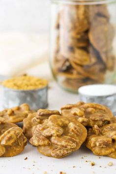 cookies with peanut butter and pecans are on the table next to two glass jars