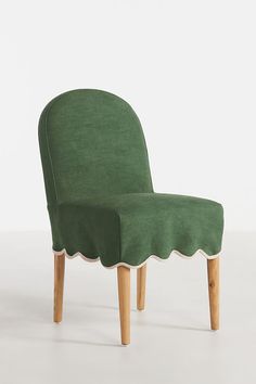 an upholstered chair with scalloped legs and a green cover on the back