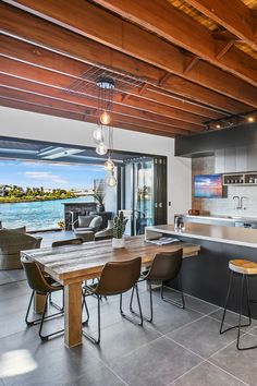 an open kitchen and dining area with large windows overlooking the water in front of it