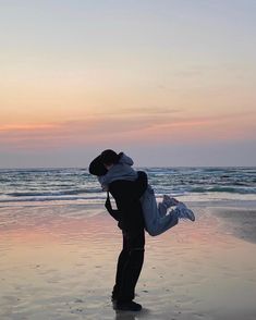 a man carrying a woman on the beach at sunset