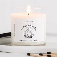 a white candle sitting on top of a table next to two black and white pencils