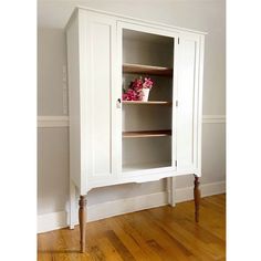 a white cabinet sitting on top of a hard wood floor