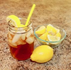 a mason jar filled with ice and lemon slices next to a bowl of sliced lemons