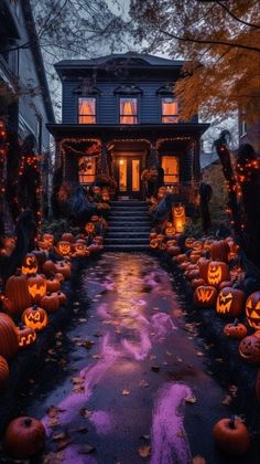 a house decorated for halloween with pumpkins on the ground and lights all around it