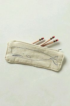 three pencils are laying on top of a piece of cloth with a whale drawn on it