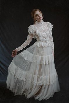 a woman in a white dress with long sleeves and ruffles on the skirt