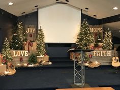 a church stage decorated with christmas trees and presents