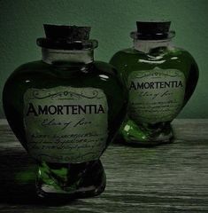 two green bottles sitting on top of a wooden table