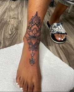 a woman's foot with a tattoo design on the left side of her leg