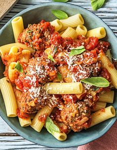 a bowl filled with pasta and meat covered in sauce, parmesan cheese and basil leaves